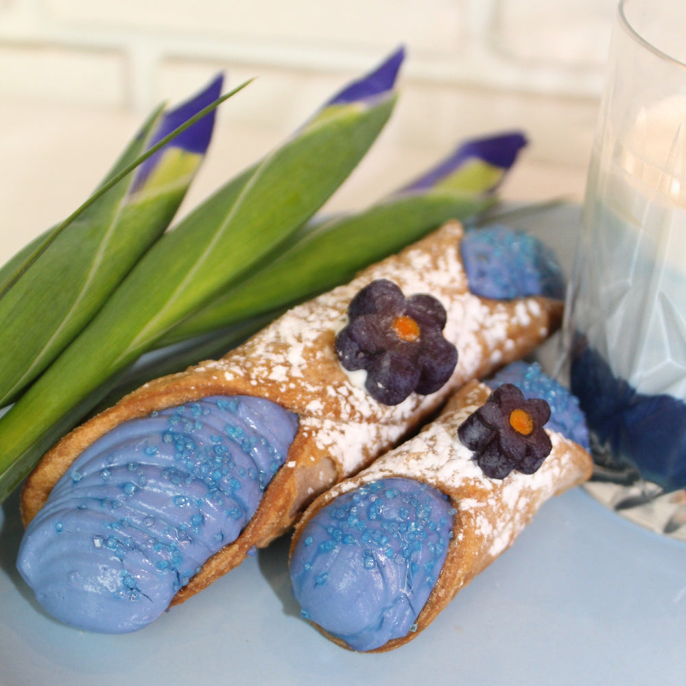 Butterfly pea flower tea, commonly known as blue matcha, is a caffeine-free, herbal tea made from an infusion of flower petals.  It's a trending flavour so we just had to blend this rich, earthy powder with our creamy, smooth ricotta, and voila--we have an incredible new gourmet cannoli with a gorgeous blue hue!  Adorning the top is a handmade marzipan flower.  This is a must try!  