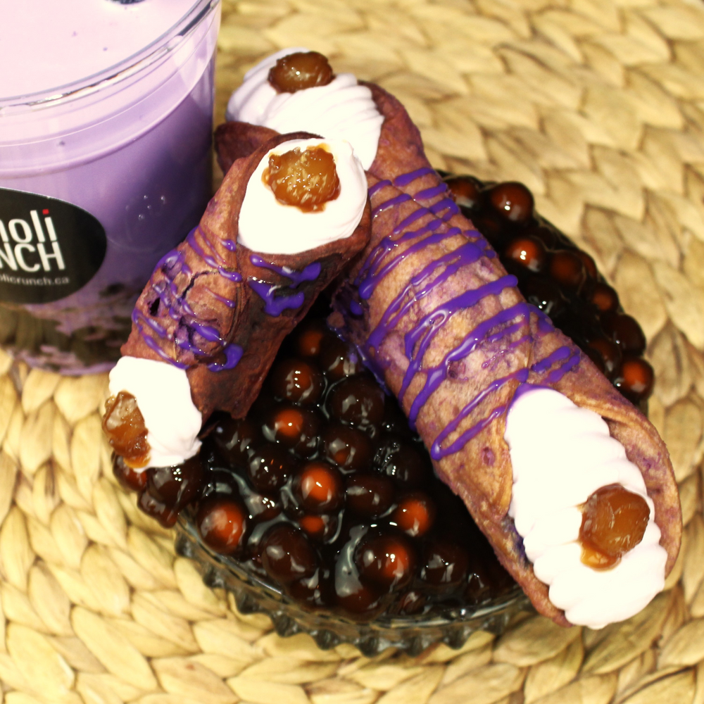 Introducing our Taro Boba Cannoli!  The blend of ground taro root, and jasmine tea into our creamy, smooth ricotta creates the exact same flavour as taro bubble tea with its sweet and nutty undertones.  Gently piped into our crispy, crunchy purple pastry shell and decorated on the ends with bobas, this delight captures the magic of the Far East's enchanting palate in a Sicilian cannoli.