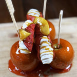 Step right into sweet enchantment with our Candy Apple Cannoli — a playful twist on two beloved classics! Crispy, crunchy red cannoli shells cradle a dreamy filling of creamy apple ricotta filling, drizzled with buttery caramel that dance across your taste buds and topped with a slice of carmelized apple. Each bite offers the crunch of a fair‑day caramel apple and the charm of an Italian bakery delight. This cannolo is autumn wrapped in pastry — a little bit cozy, and entirely irresistible!