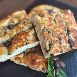 Enjoy the flavours of Italy with our Authentic House-Made Focaccia, topped with Kalamata olives and aromatic basil. This soft, pillowy bread is baked to golden perfection, offering a delicate balance of savoury olive richness and the fresh, fragrant essence of basil. With its irresistible texture and bold flavors, our focaccia makes the perfect accompaniment to any meal or a delicious standalone treat. Made fresh daily, it’s a true taste of Italy in every bite