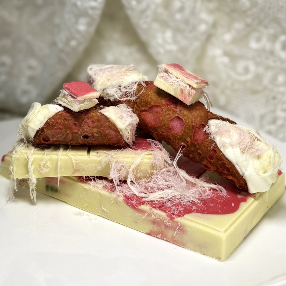 Meet the VIRAL sensation: the Pink Angel Hair Chocolate Cannoli!!! This eye-catching treat features a delicate pink, crisp cannolo shell spun on the ends with pomegranate and vanilla angel hair, giving them a whimsical aesthetic.&nbsp; Inside, each shell is filled with ultra-creamy ricotta blended with tangy cherry, creating a luscious, fruity filling that balances sweetness with a hint of tart. Perched on top is a decadent square of our housemade Pink Angel Hair Chocolate! 
