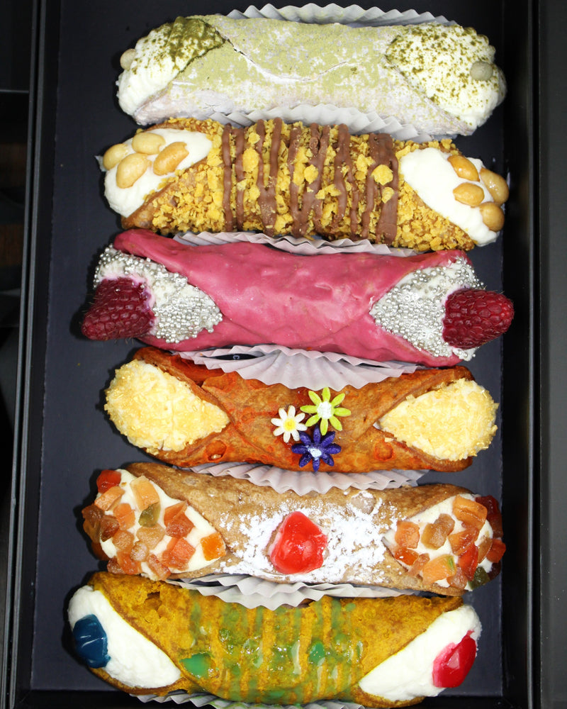 Introducing the Setbox Collection of 6 Large Cannoli – a curated assortment that encapsulates the essence of indulgence, craftsmanship, and diverse flavors. Elevate your cannoli experience with this exclusive collection that offers a delightful array of tastes and textures, perfect for every occasion.Within our Gourmet SetBox of 6 Large Cannoli are:  (Top to Bottom)  The White Coffee, Fruckies, The Love Potion, The Bouquet, Frutta Scorza, and The Gusher.     