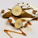 This decadent treat features a crispy, golden cannoli shell filled with a velvety blend of sweet banana cream and rich toffee, creating a luscious, silky and indulgent filling. Topped with a banana chip and trimmed on the ends with a morsel of toffee, each bite delivers a delightful mix of sweetness and crunch. The Banoffee Cannoli is the ultimate dessert for those who crave a deliciously unique twist on the classic Italian treat!