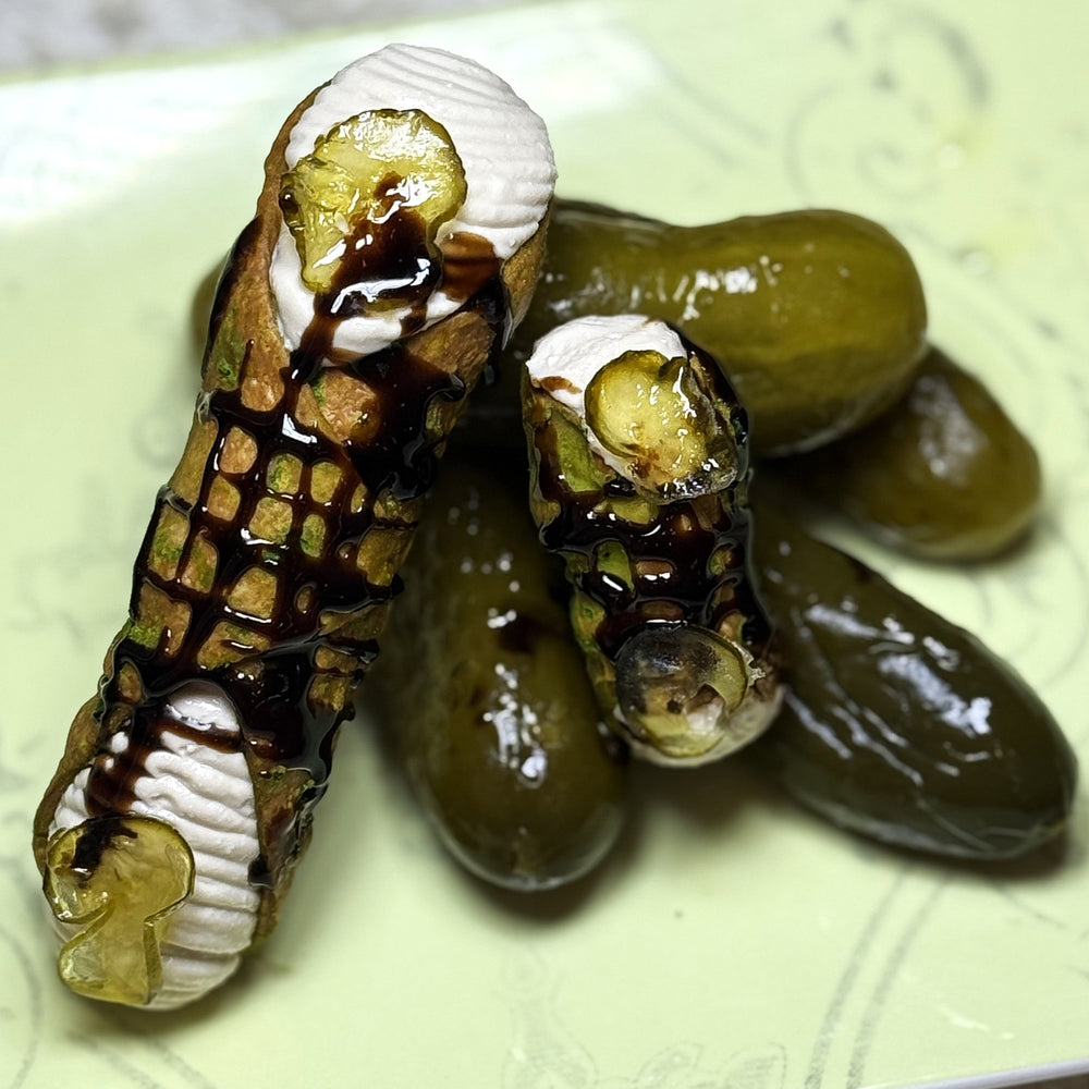 Dive into a daring, trending flavour adventure with our Sugar'd Pickle Cannoli—a treat that’s as playful as it is unexpected! Each crispy cannoli shell is filled with smooth, honey-balsamic-infused cream, perfectly balanced by a candied slice of pickle on the ends. The result? A wildly unique snack that blends sweet and sour in delicious harmony. Every bite is a surprise party for your taste buds, making this cannolo the conversation starter at any gathering. 