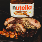 Fill your sweet tooth with our decadent Nutella Cannoli, a treat that combines Nutella's rich, creamy goodness with the classic Italian dessert. Each cannolo features a crispy cannoli shell covered in chocolate then dusted with hazelnuts and filled to the brim with a velvety Nutella cream that melts in your mouth. To add a burst of nuttiness, a whole hazelnut trims the ends perfectly blending Italian tradition and modern indulgence. Buon apetito tutti!