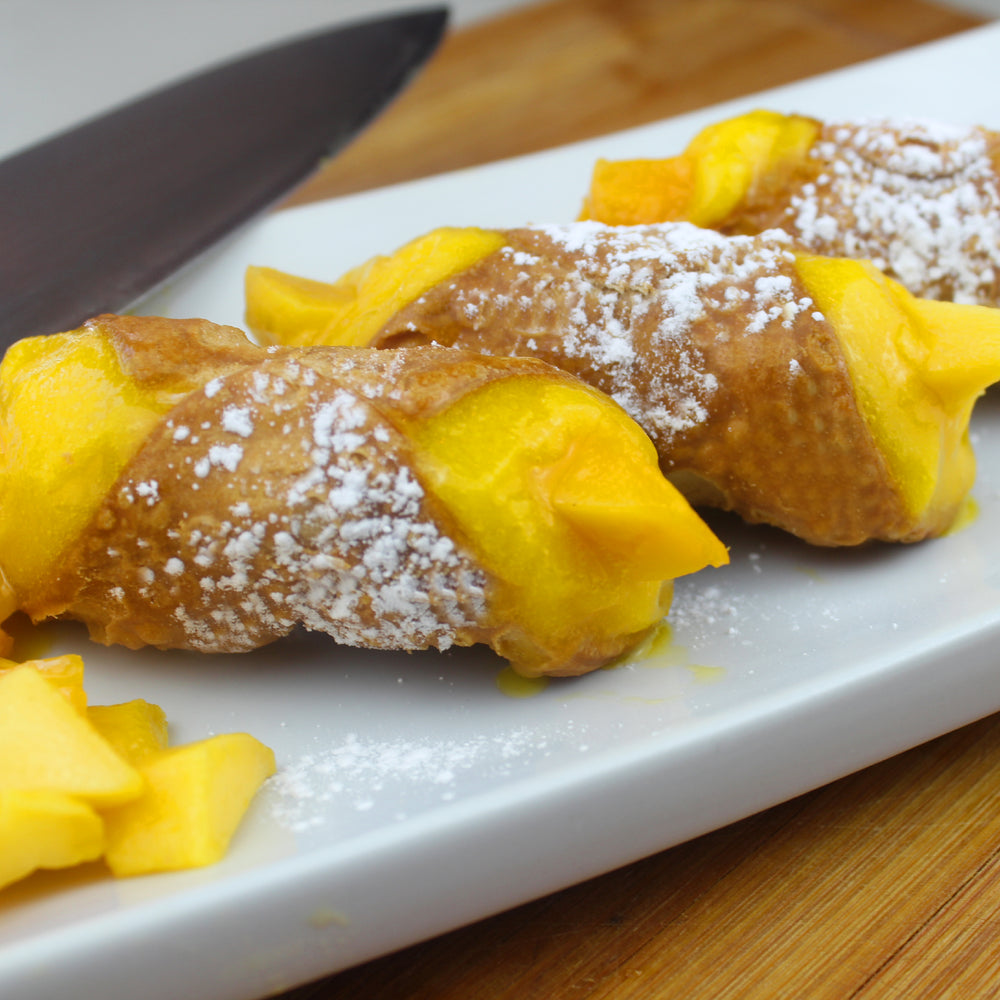 DAIRY FREE:  The tropics are hot and sexy!  What can be sexier than the sweet flavour of a sun-ripened mango made into a sorbet and then combined with our homemade, crispy crunchy deep-fried cannoli shell?  They are finished with a dusting of powdered sugar and pieces of fresh mango on the ends to complete your trip down south!    www.cannolicrunch.ca