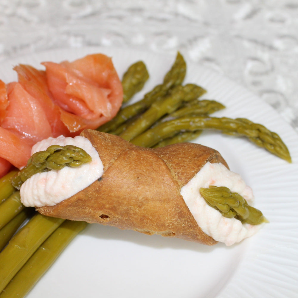 Salmon mousse with pickled asparagus is an elegant appetizer that combines the rich, creamy flavour of salmon mousse with the tangy, vinegary taste of pickled asparagus.  Our creamy, smooth ricotta is combined with smoked salmon and herbs then piped into our crispy, crunchy pastry shell and adorned with asparagus tips on the ends.  It's luxury in a couple of bites!